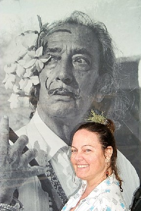 A black and white photo of Dali is behind a woman with dark hair pulled up into a bun.  A weed is sticking out of the top of her head.  Yes, it is a weed.  They grow in Florida.  It is a weed.  I swear it.